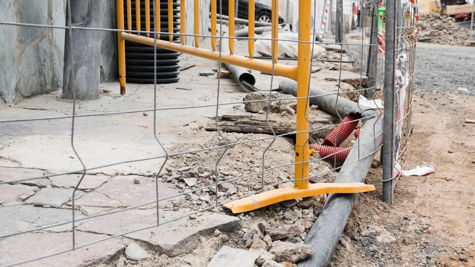 בסיס של גדר זמנית ומחסומים צהובים על מדרכה עירונית ליד אתר בנייה